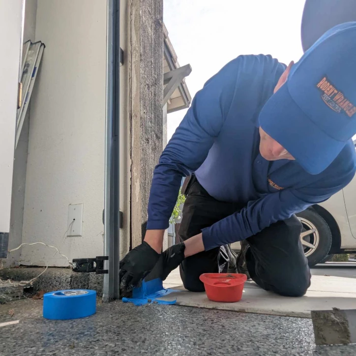 a rodent wrangler technician providing rodent exclusion service to seal a gap at the base of the garage roll up door to keep out rats and mice